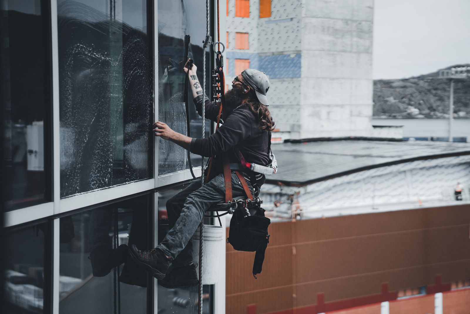 Rope-access technician washing commercial windows